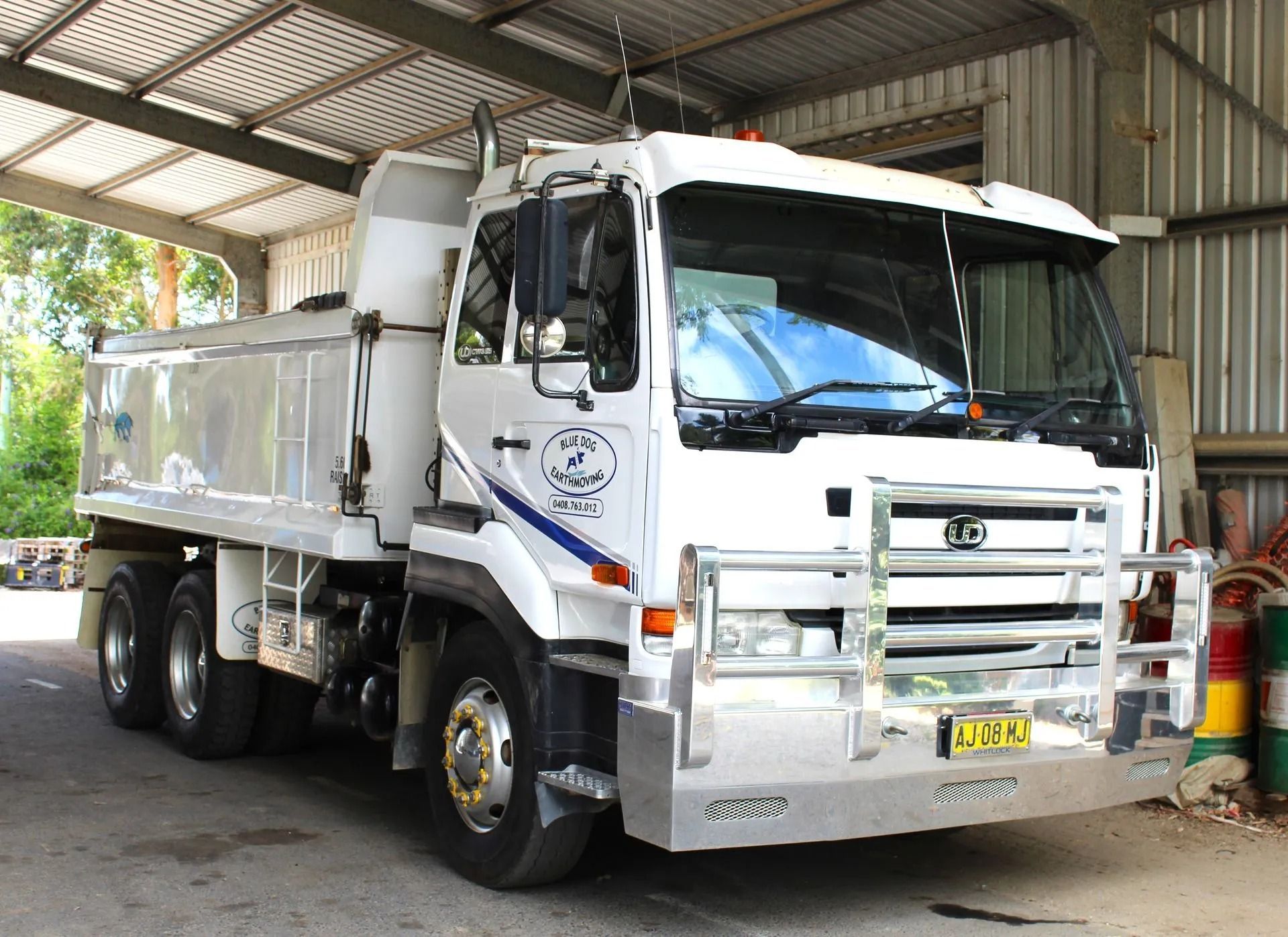 White Dump Truck Parked Under a Corrugated Metal Roof — Blue Dog Earthmoving Landscape Supplies in Urunga, NSW