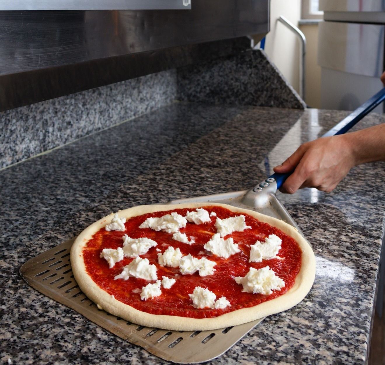 Una pizza è appoggiata su un piatto accanto a una forchetta.