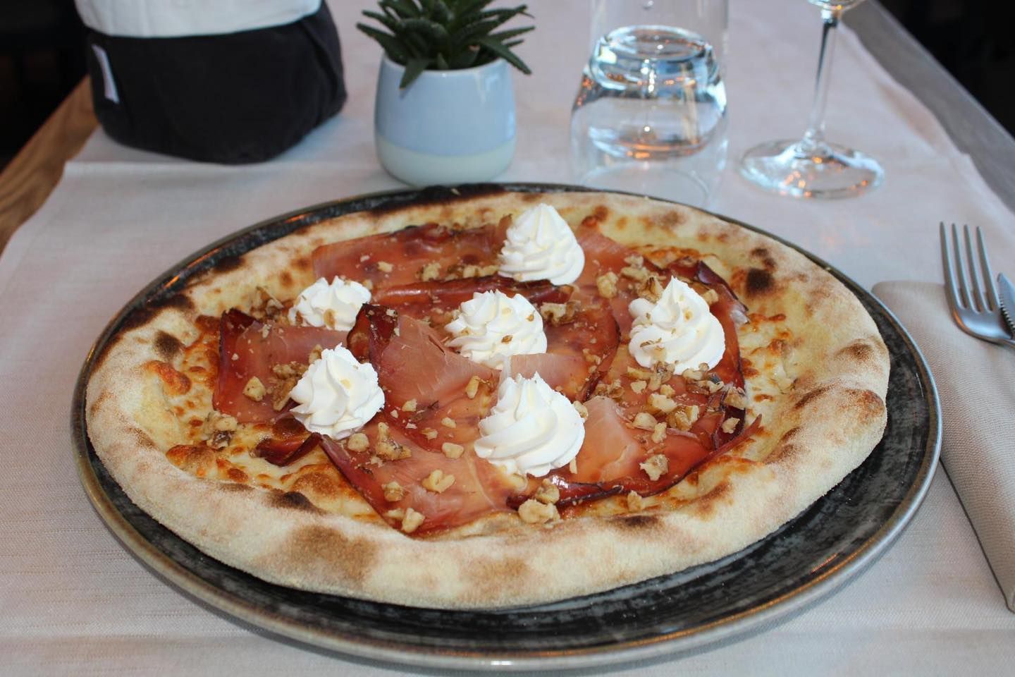 Una pizza con panna montata sopra è su un piatto su un tavolo.