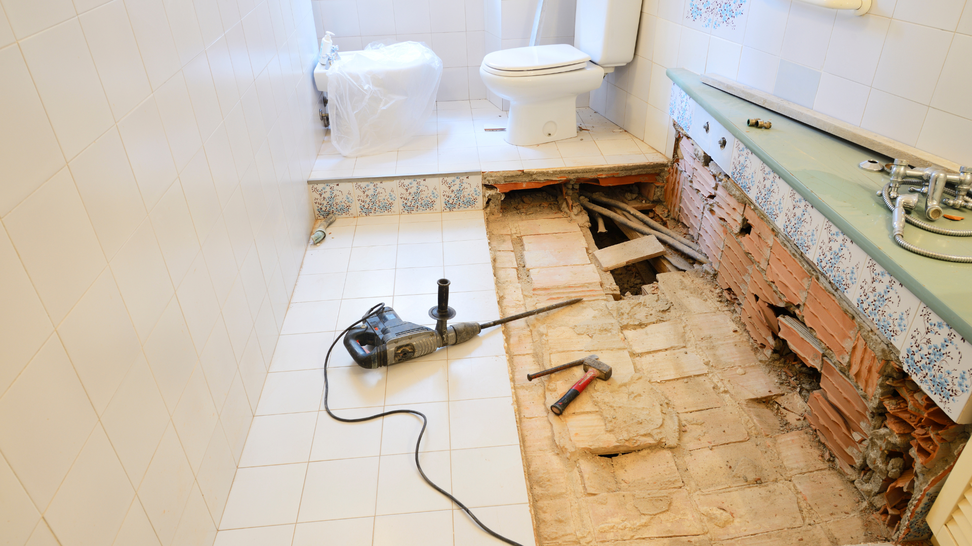 A bathroom with a toilet and a drill on the floor.