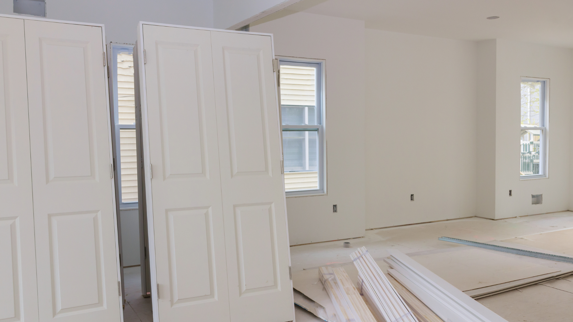 A room in a house under construction with white doors and windows.