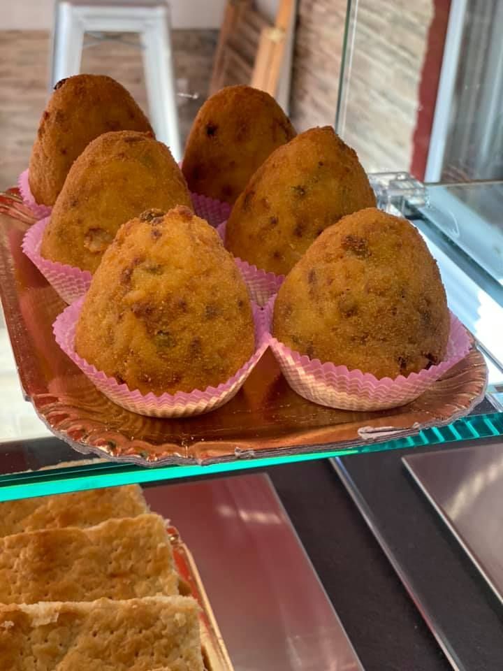 Un vassoio di cibo fritto con involucri rosa su un bancone di vetro.