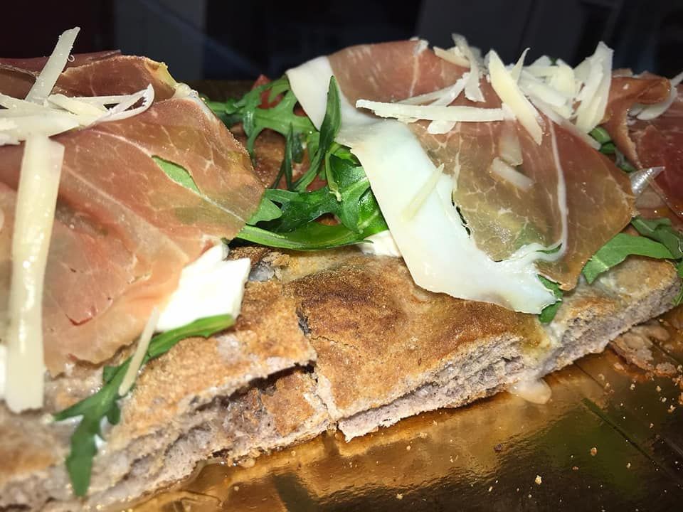 Un primo piano di una pizza con carne e formaggio sopra