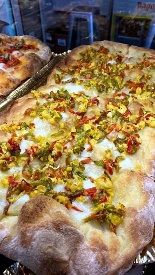 Una pizza con molti condimenti è appoggiata su un vassoio.