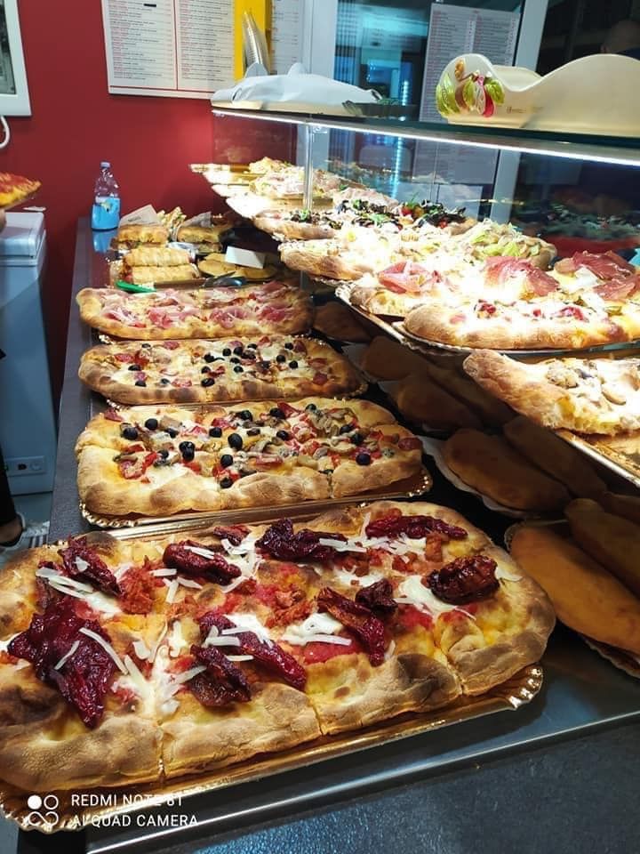 Un mucchio di pizze sono appoggiate su vassoi su un tavolo.