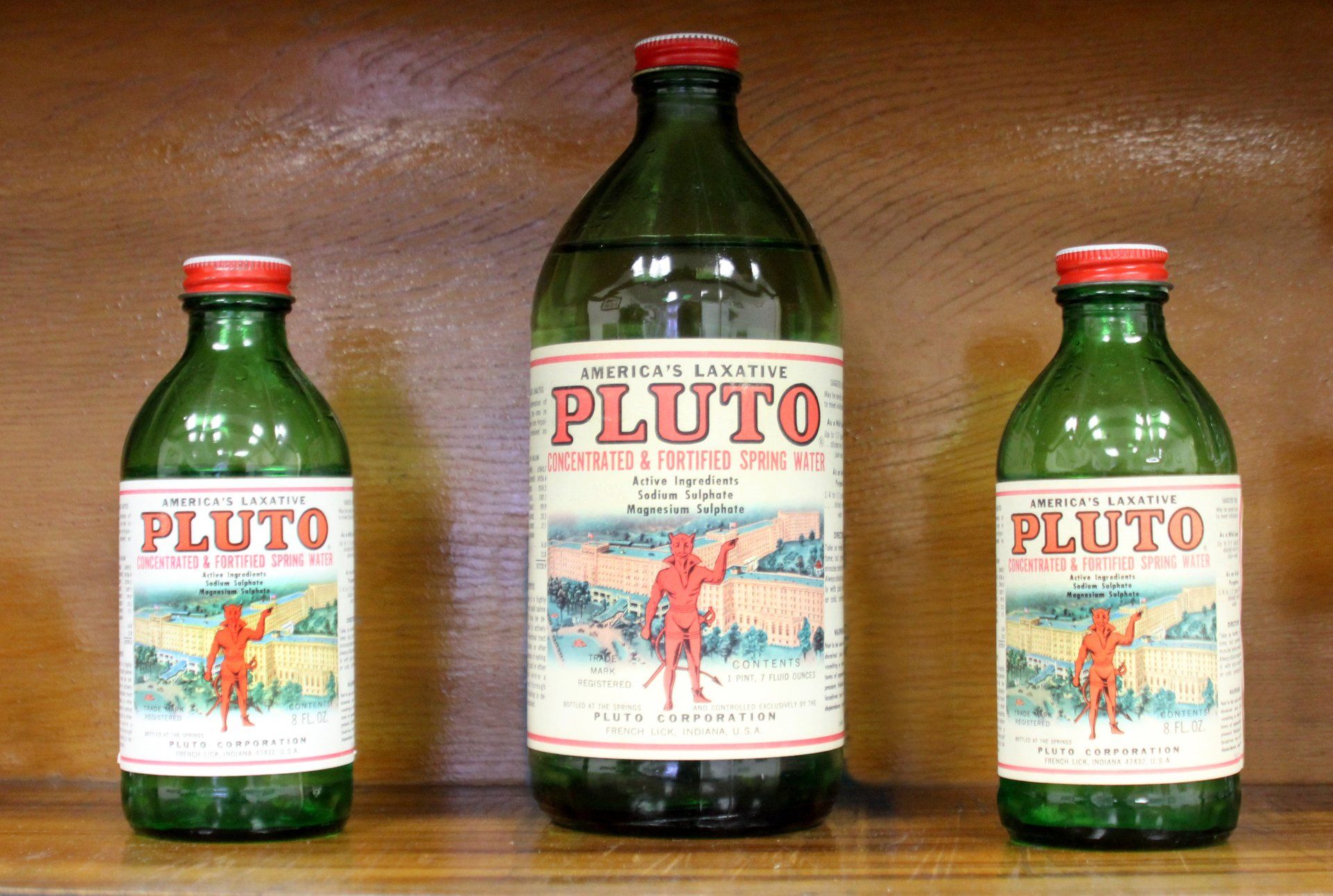Three bottles of Pluto sit on a wooden shelf