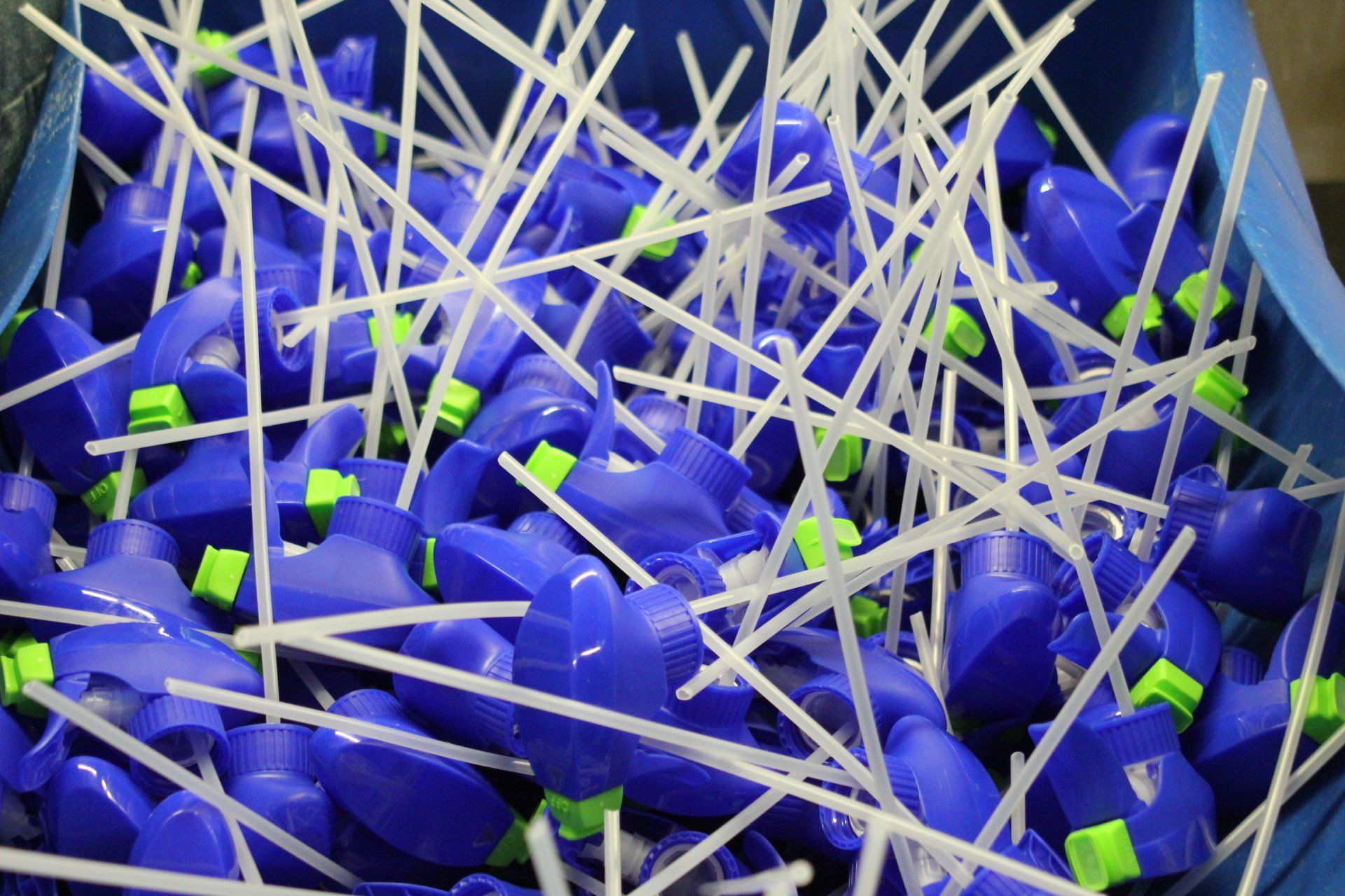 A pile of blue plastic bottles with green caps and white straws.
