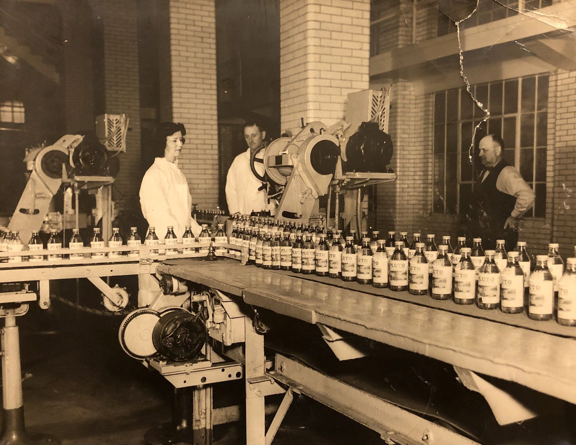 A black and white photo of a Pluto conveyor belt filled with bottles