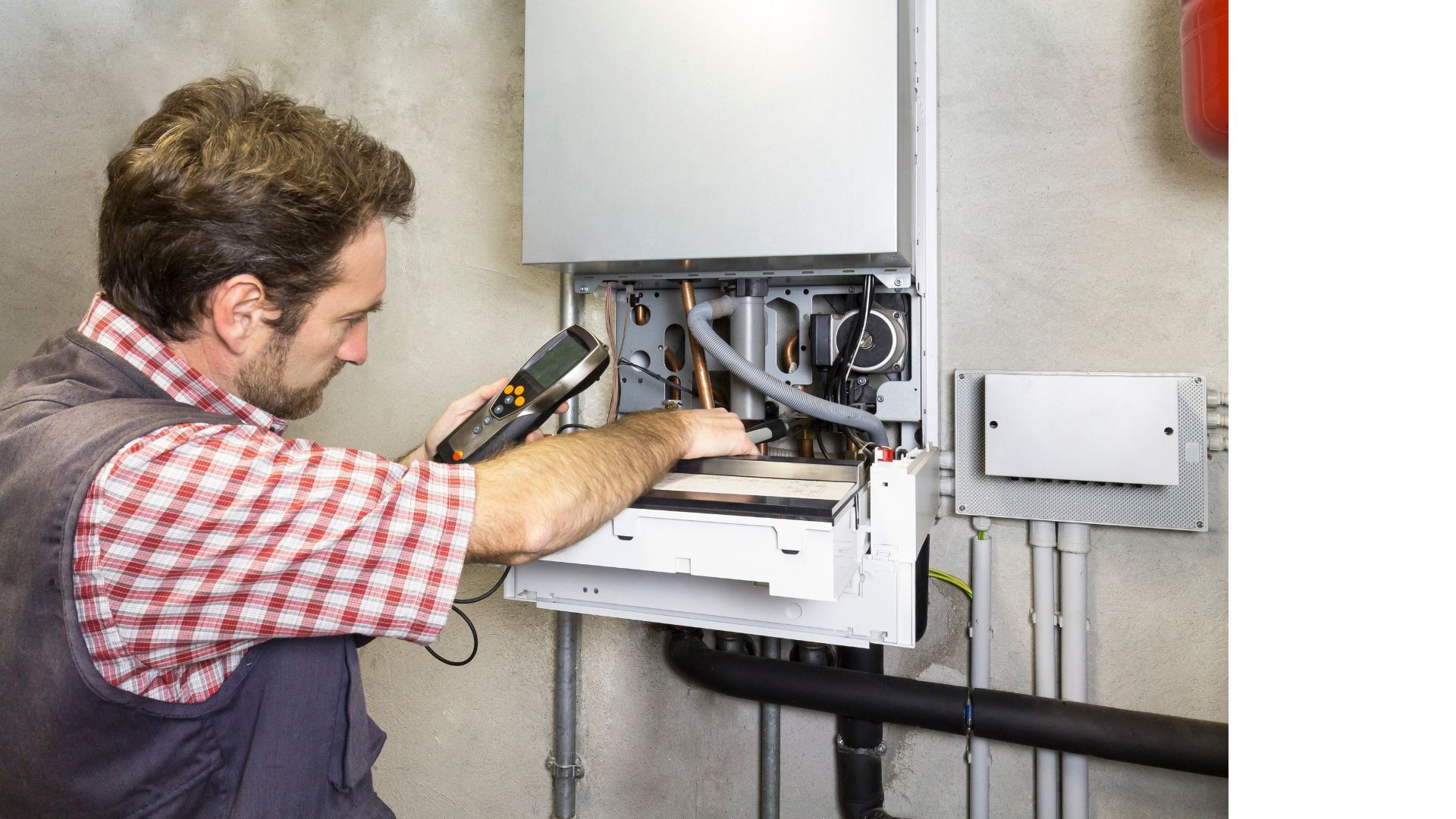 A man is working on a boiler with a thermometer.