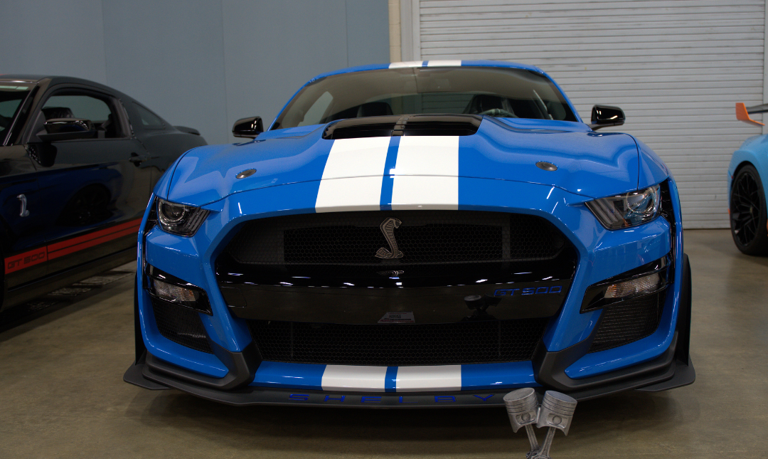 Grill view of bright blue Shelby sports car with white hood stripes