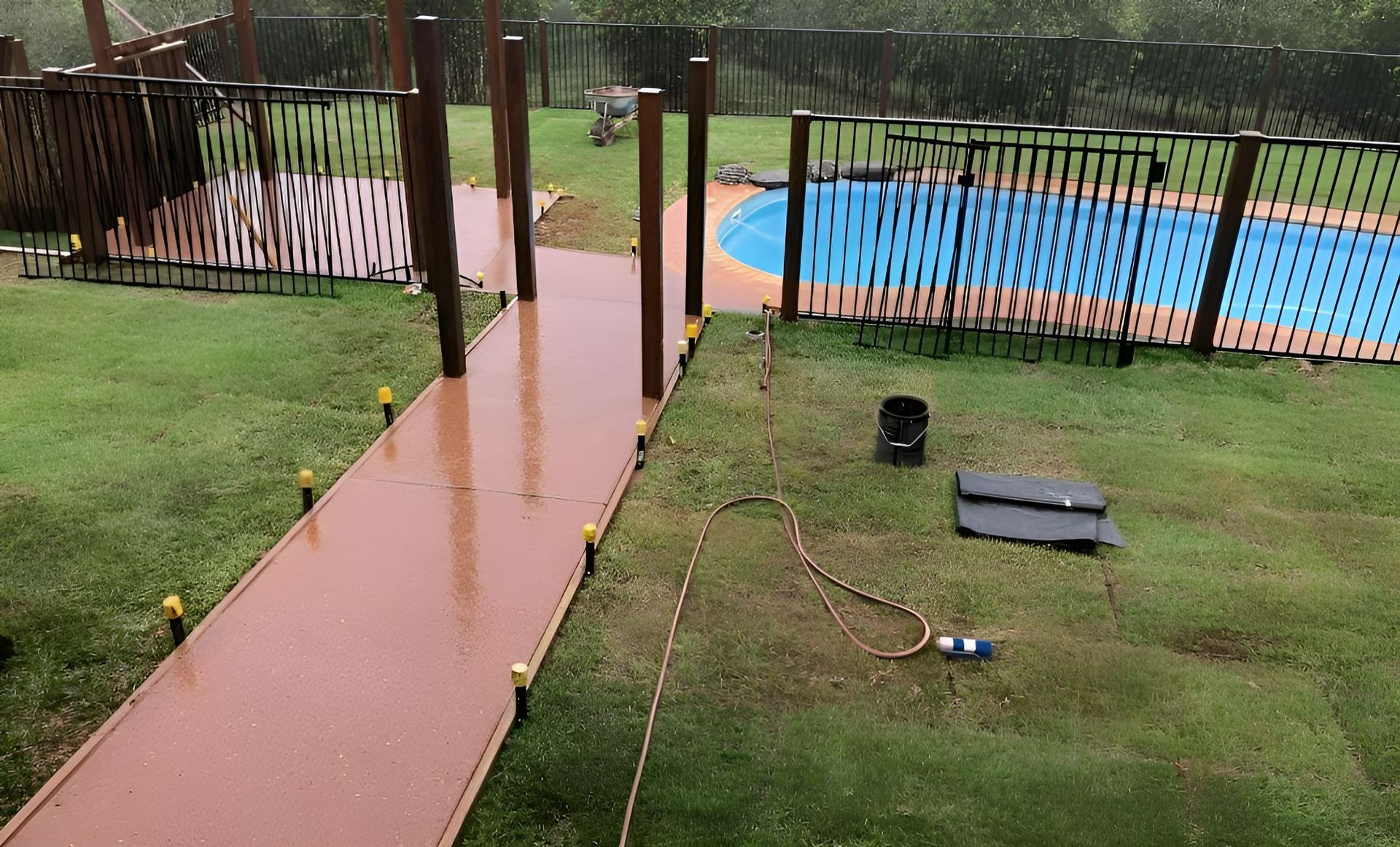 Rainy Backyard With a Red Pathway Leading to a Pool — Northern Rivers Concrete Construction in Casino, NSW