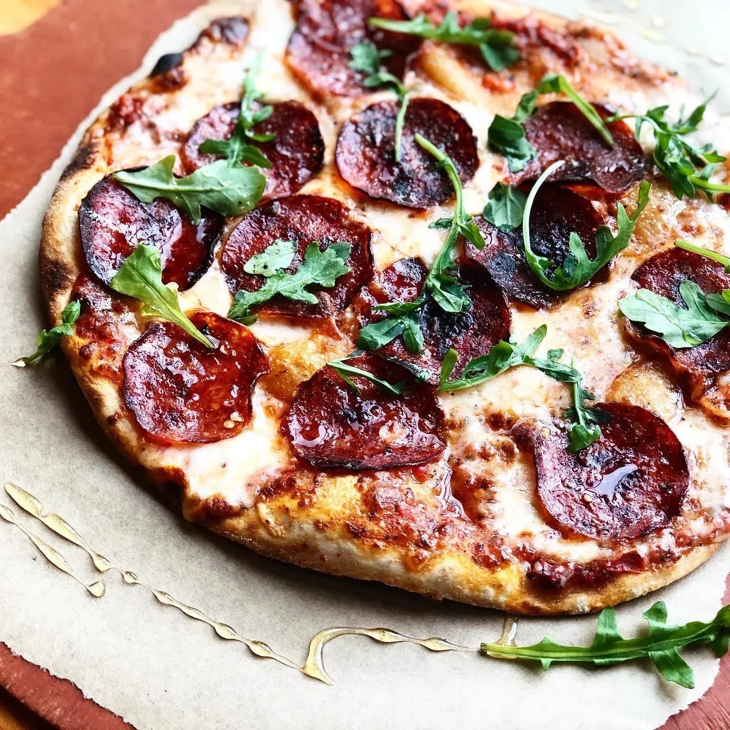 Pepperoni pizza with arugula on parchment paper.