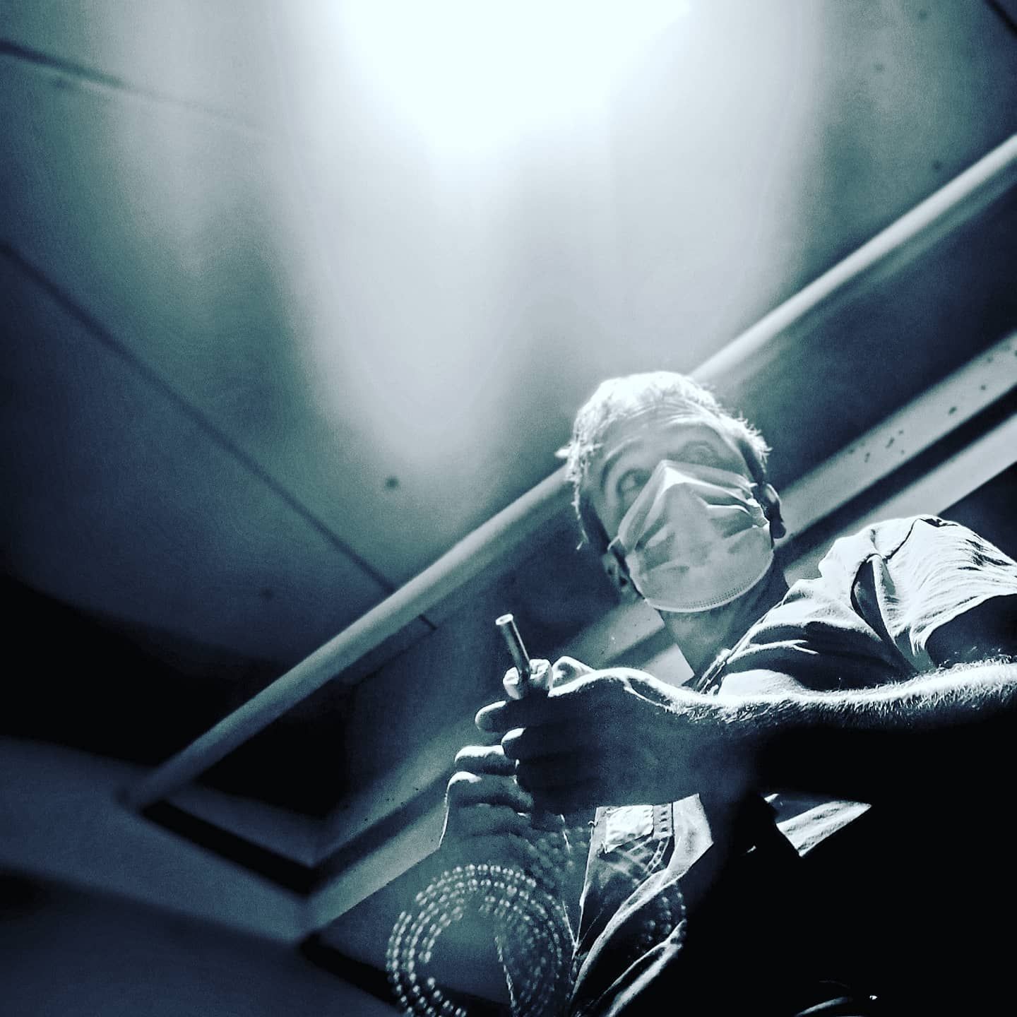 A man wearing a mask is holding a bottle