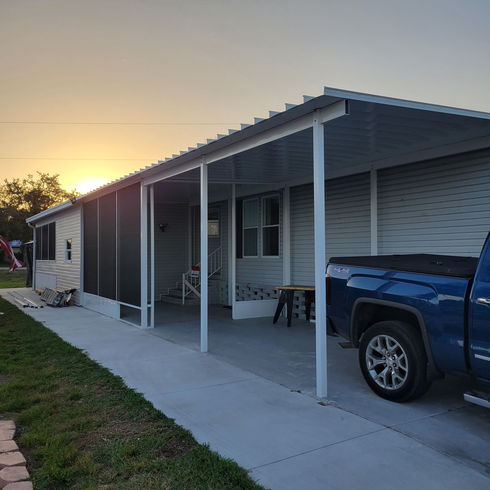 A blue truck is parked in front of a house with a covered porch