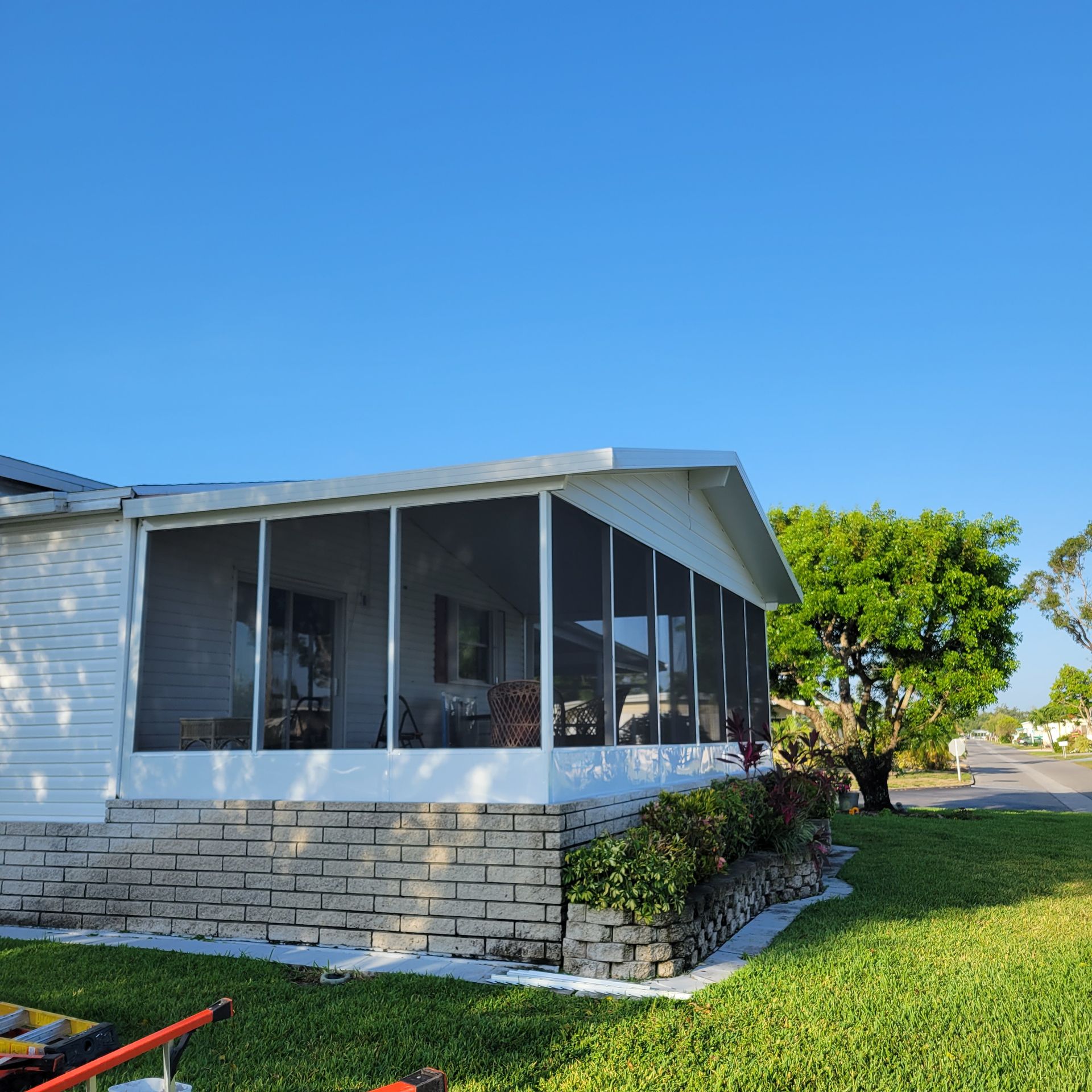 A white mobile home with a screened in porch