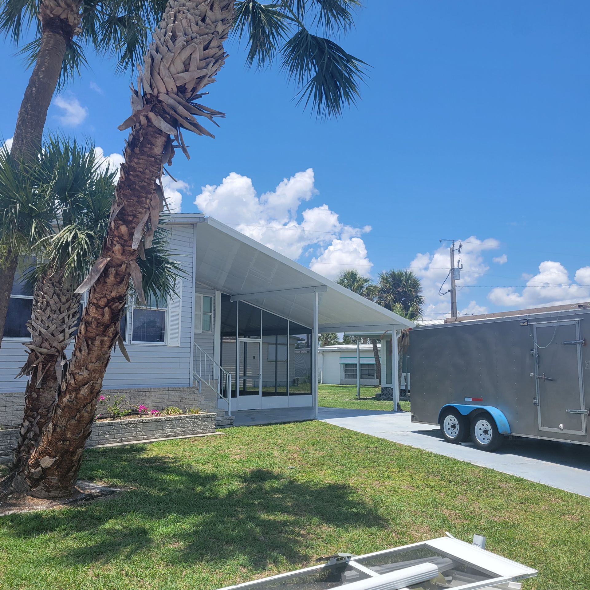 A trailer is parked in front of a house on a sunny day.