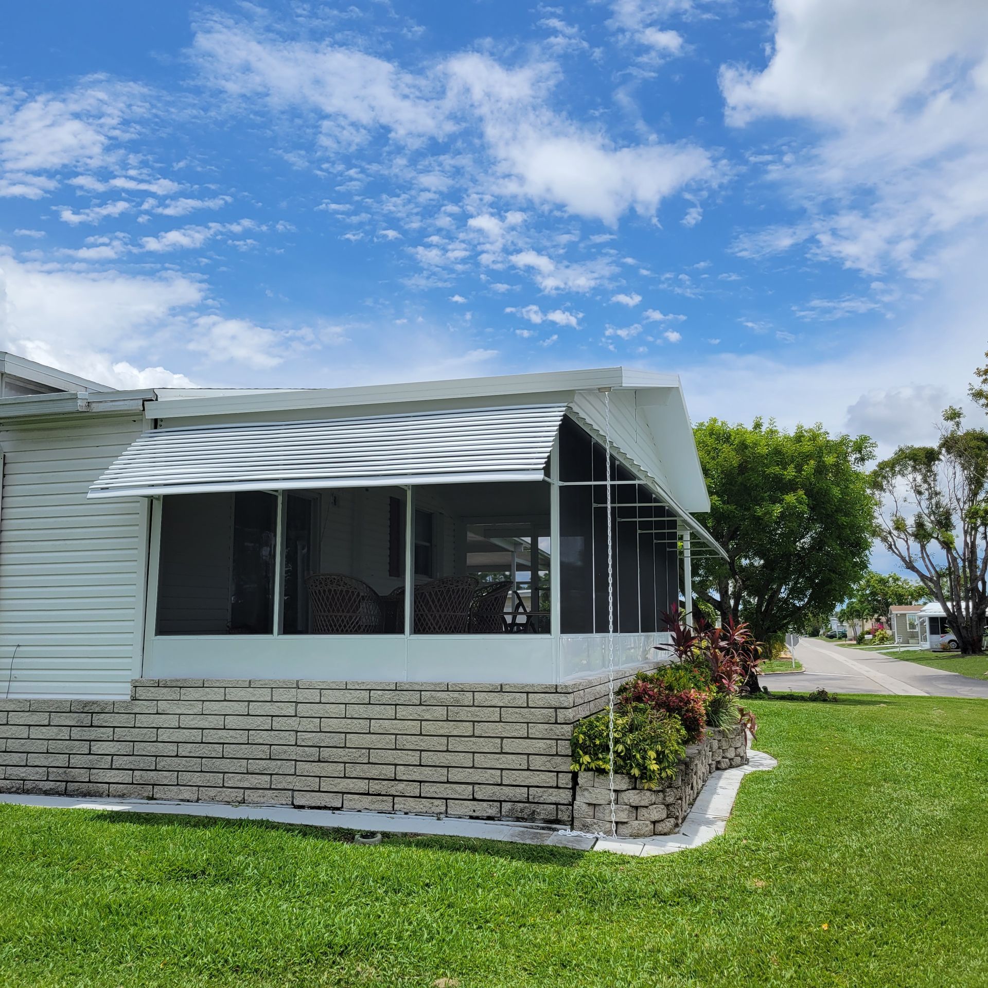 A mobile home with a screened in porch and awning.