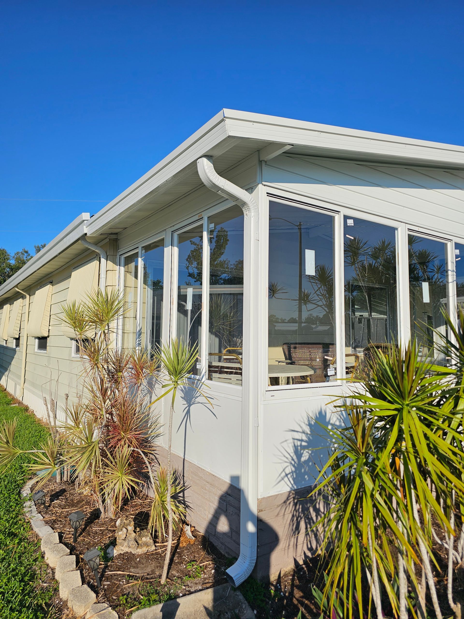 A white house with a lot of windows is surrounded by trees and bushes.