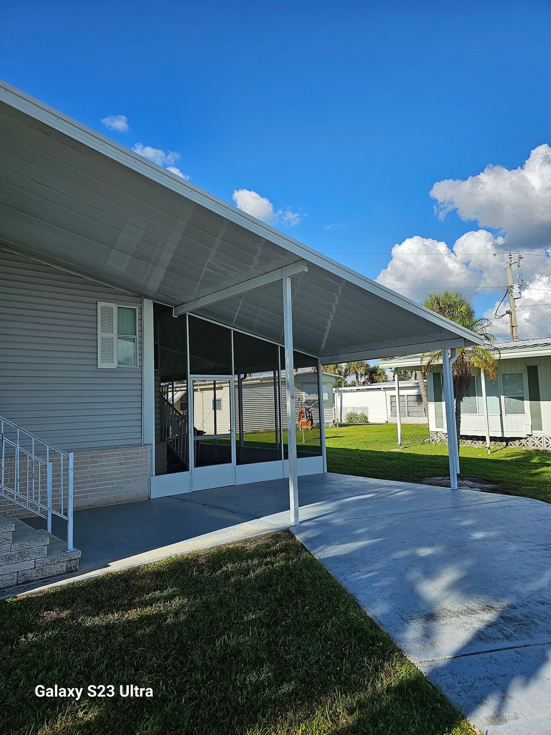 A mobile home with a screened in porch and a covered walkway.