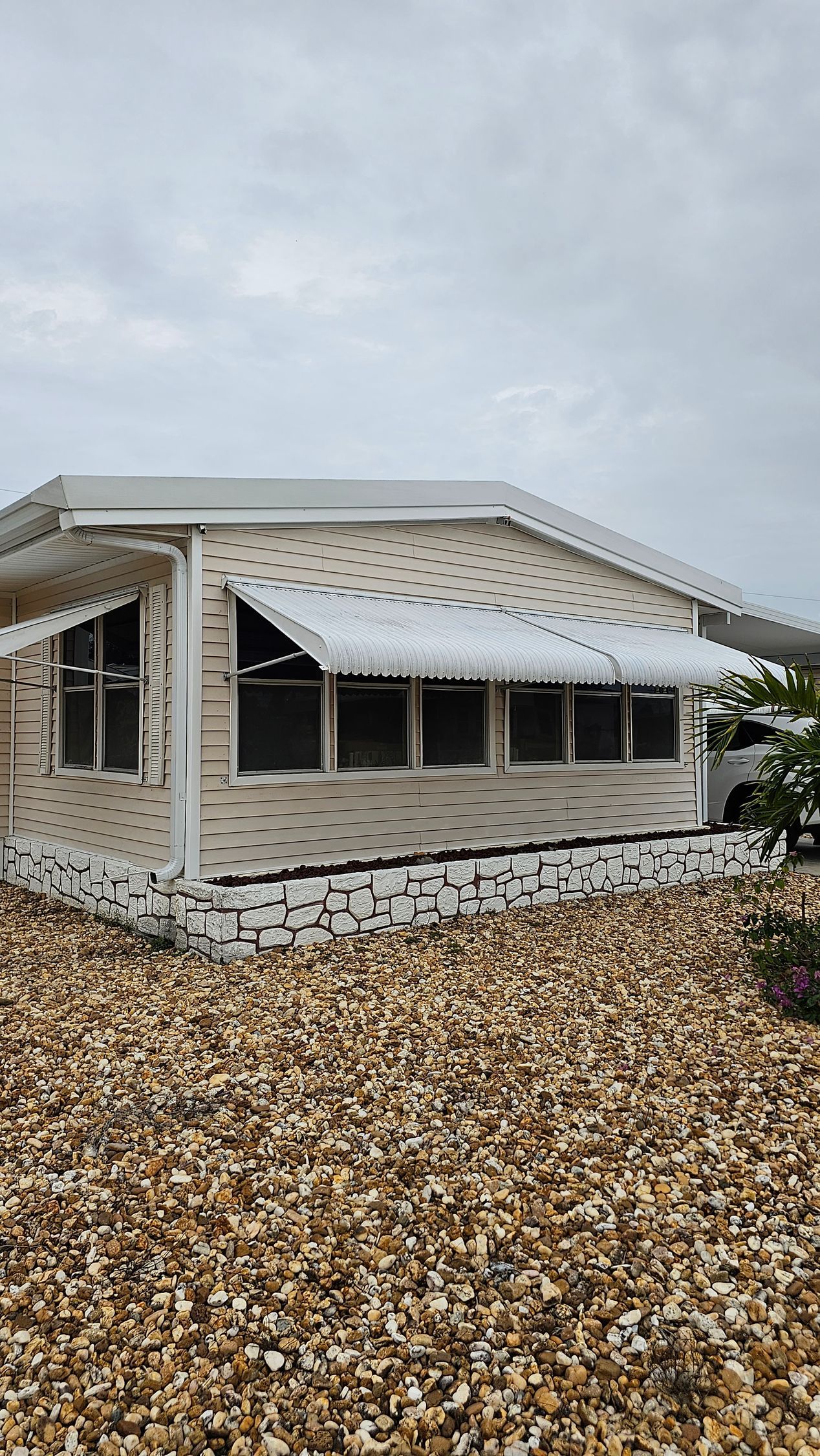 A small house with a white awning is sitting on top of a pile of gravel.
