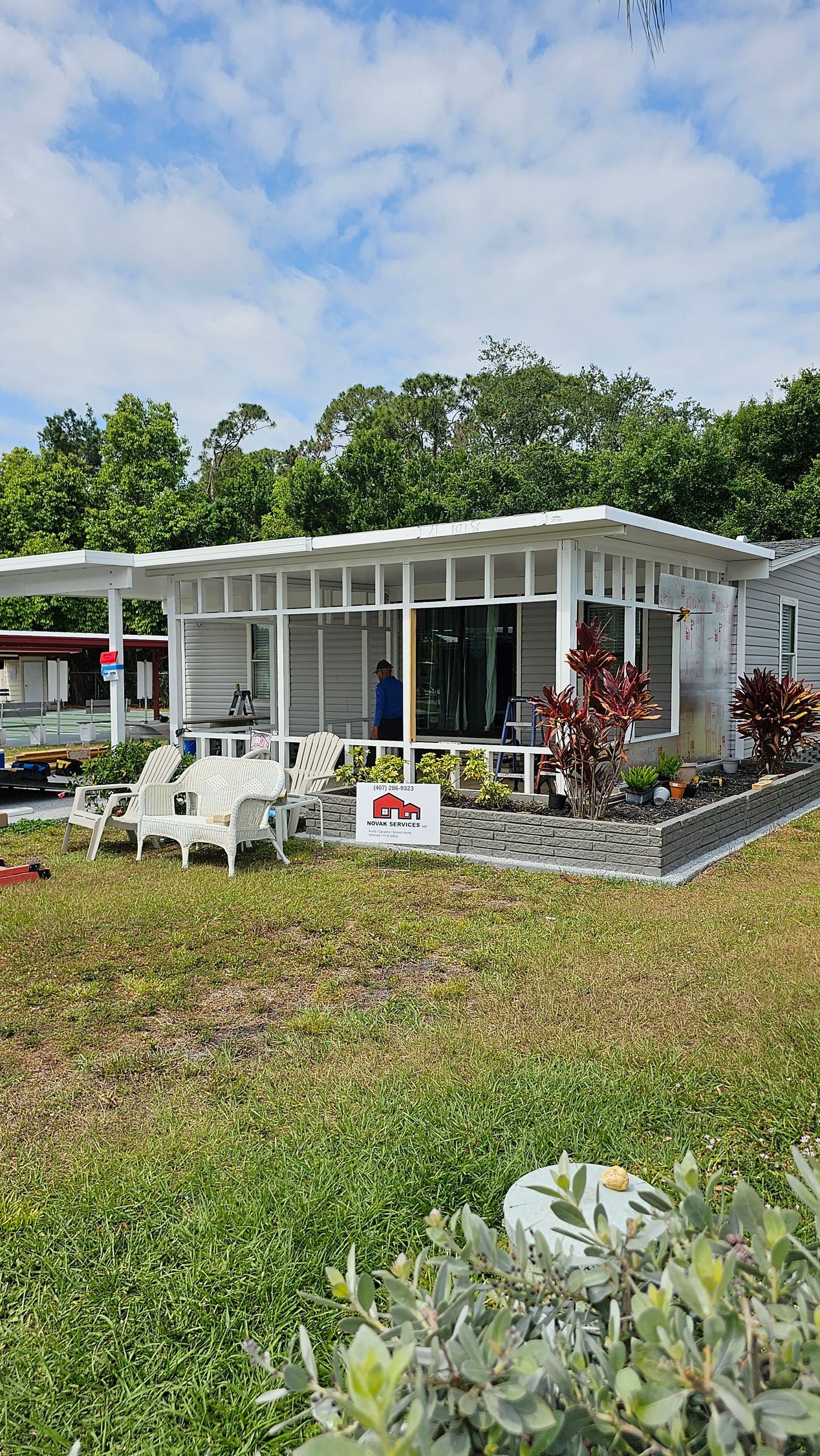 A white house is sitting on top of a grassy hill surrounded by trees.