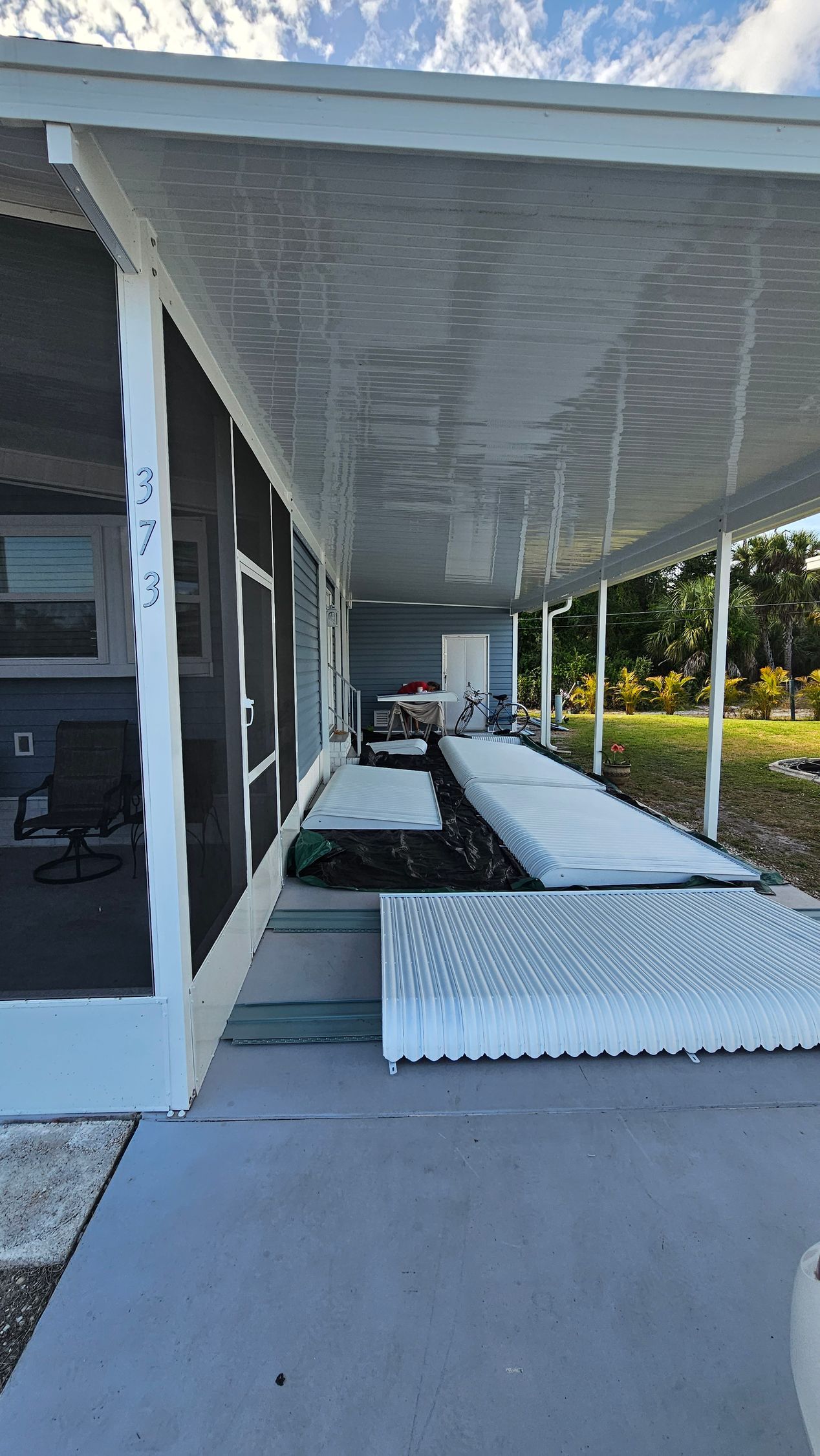 A mobile home with a screened in porch and a ramp.
