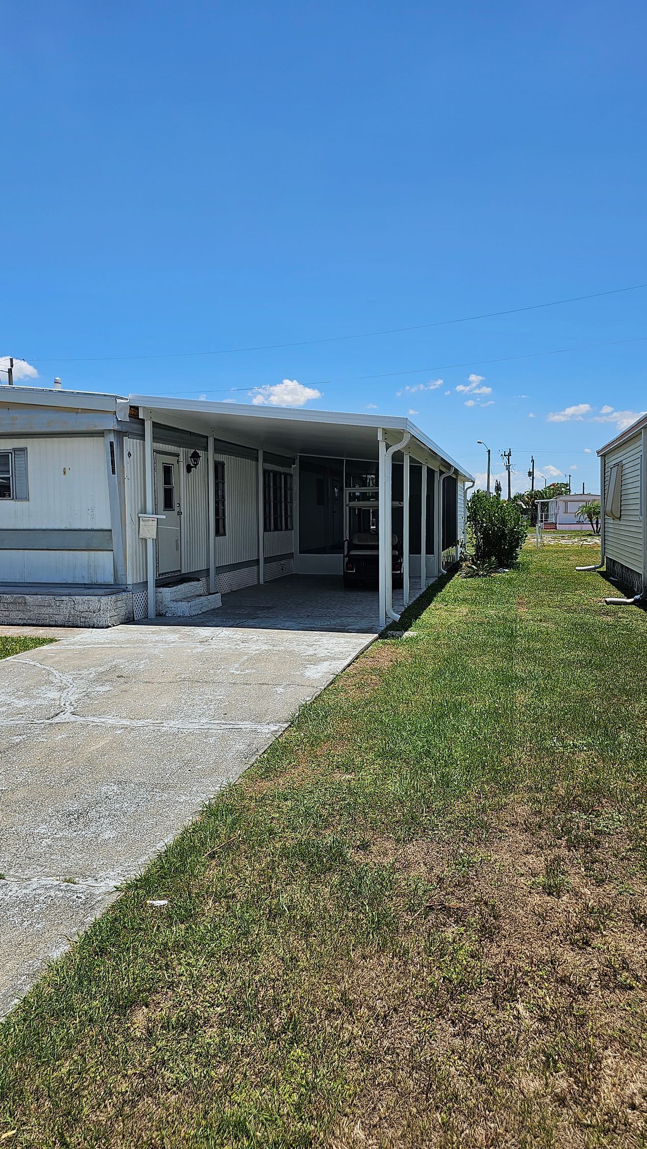 A mobile home with a covered porch and a car parked in front of it.