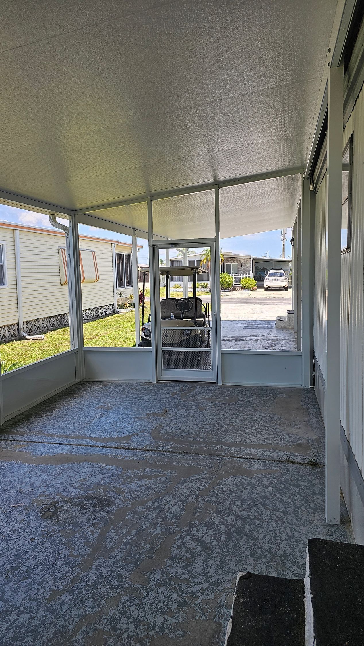 There is a covered porch with a golf cart in the background.