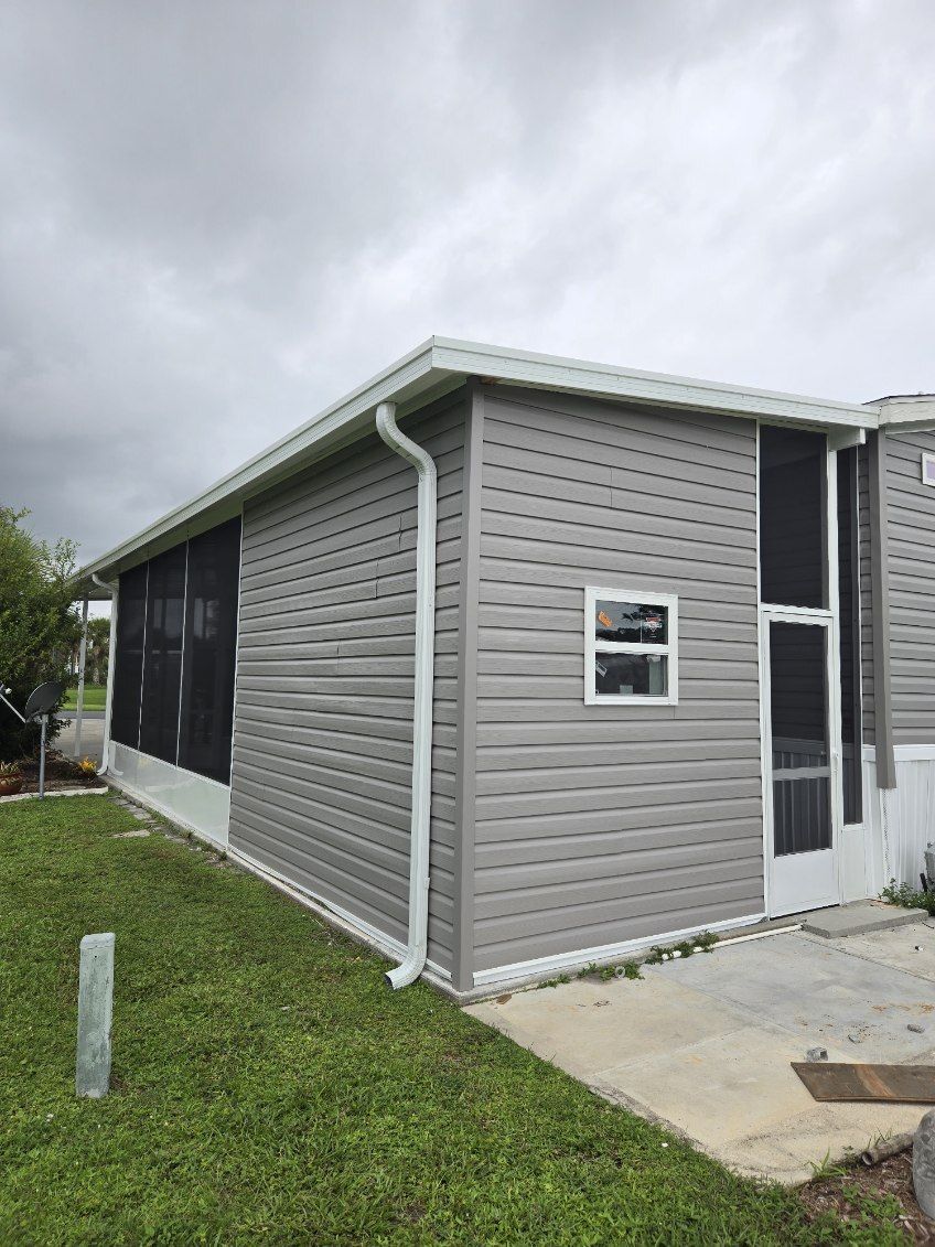 A mobile home with a screened in porch and a window.