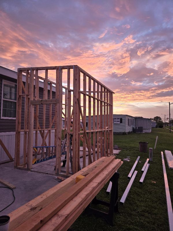 A mobile home is being built with a sunset in the background.