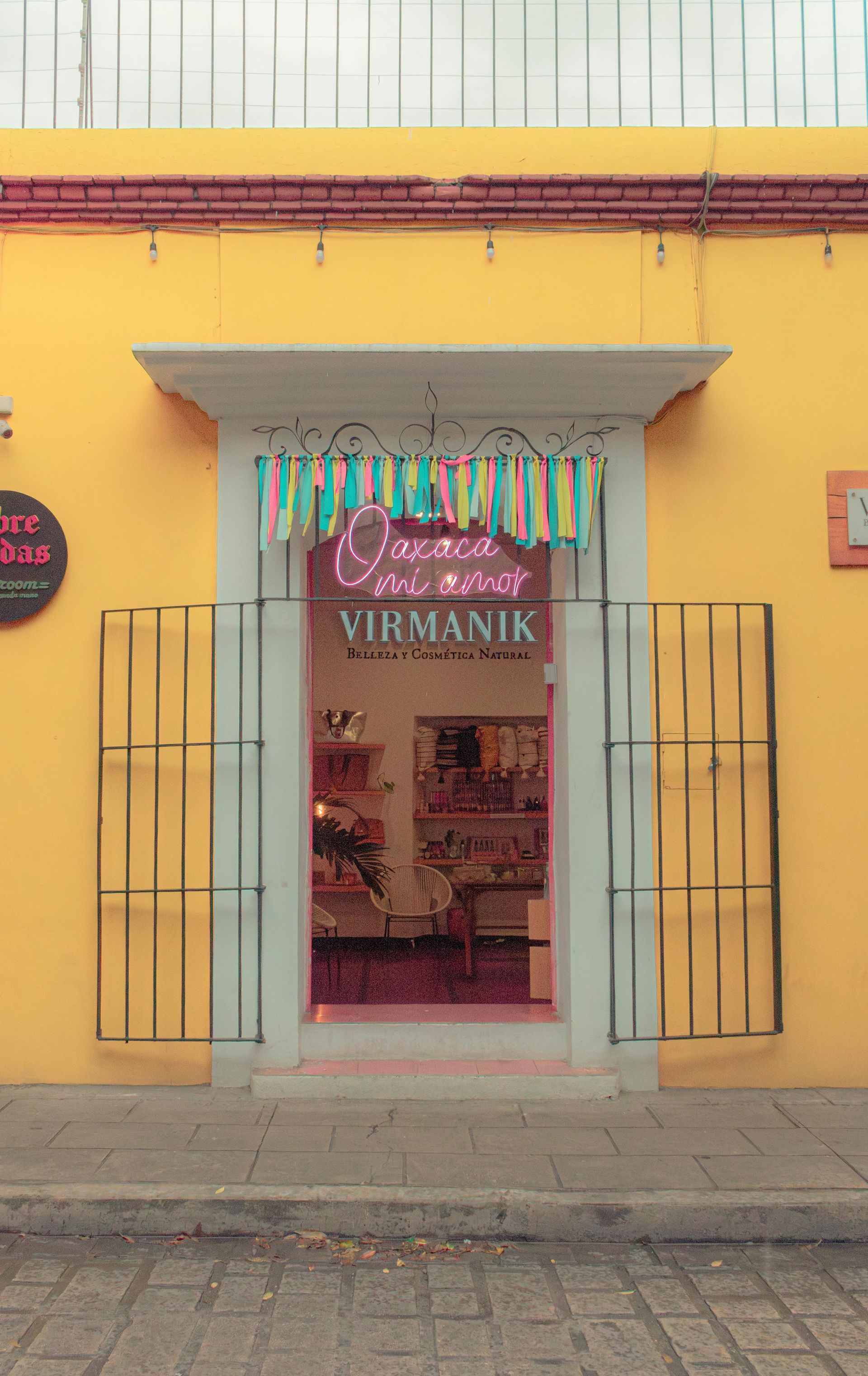 A yellow storefront with a pink-lit interior entrance marked