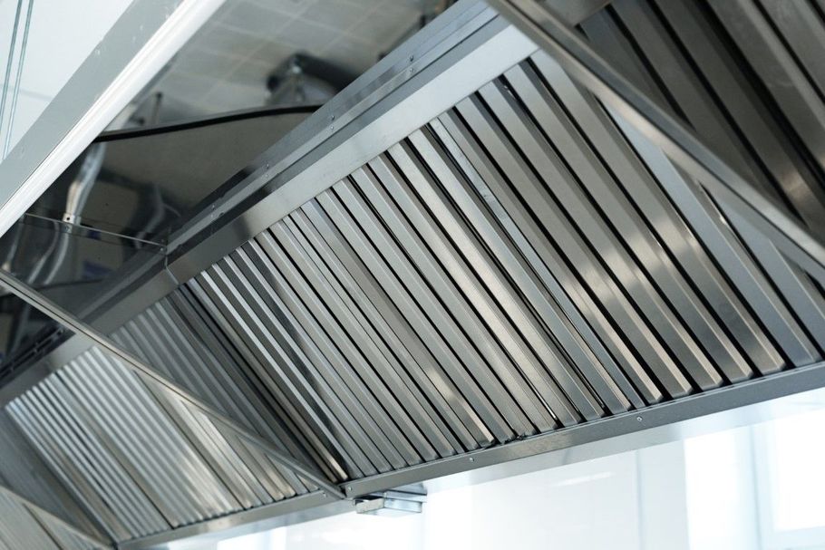 Stainless steel kitchen range hood with angled vent slats mounted under a cabinet