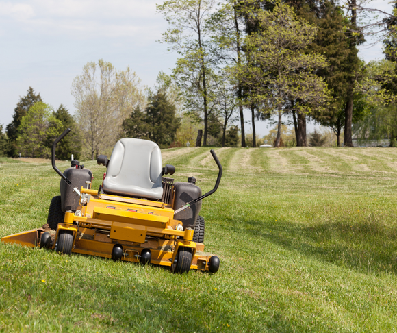 A zero-turn lawn mower in the process of mowing a lawn.