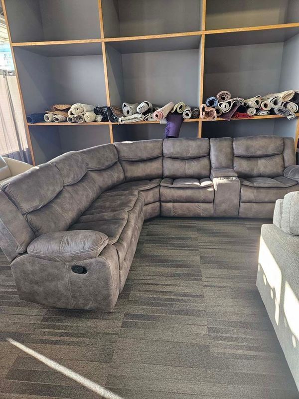 Gray sectional sofa in a showroom setting with dark shelves in the background.