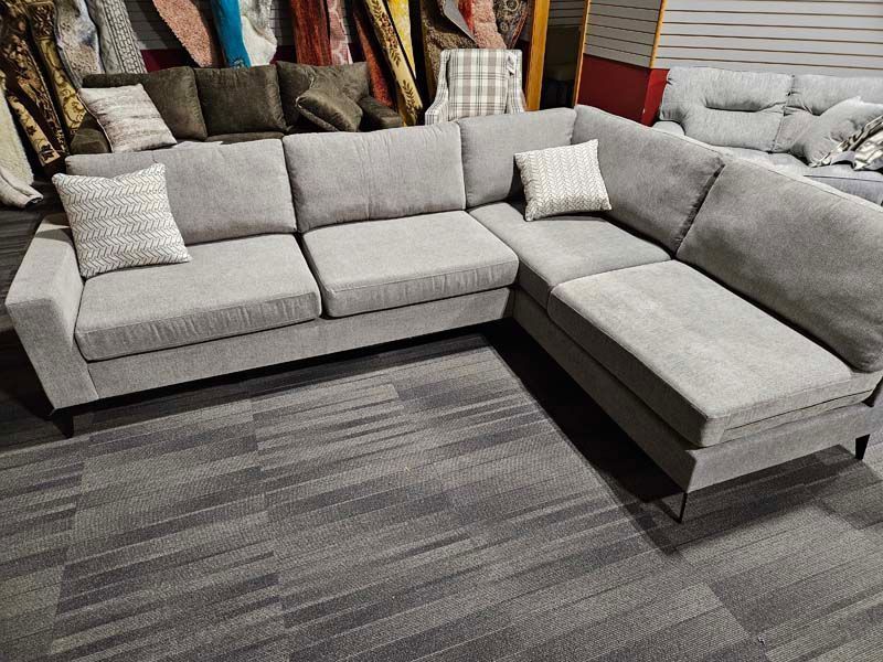 Gray sectional sofa with two white throw pillows in a showroom.