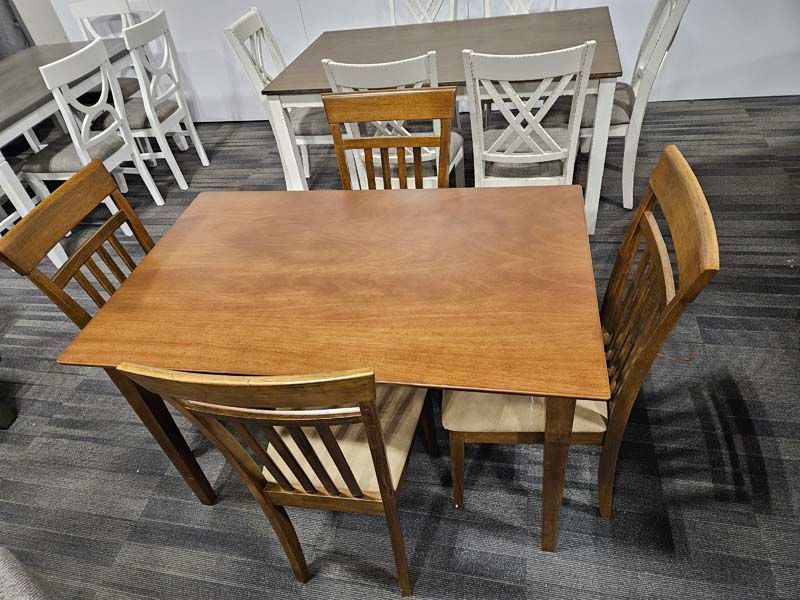 Wooden dining table with four chairs; others in the background.