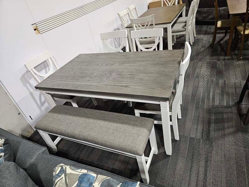 Dining table set with gray tabletop and white chairs and bench.