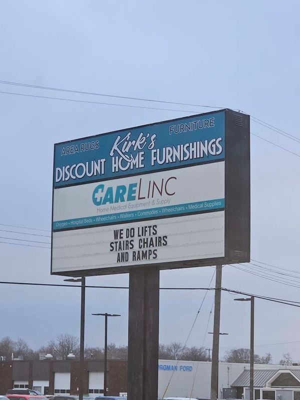 Sign for Kirk's Discount Home Furnishings. Below is Carelinc, offering lifts, chairs, stairs, and ramps.