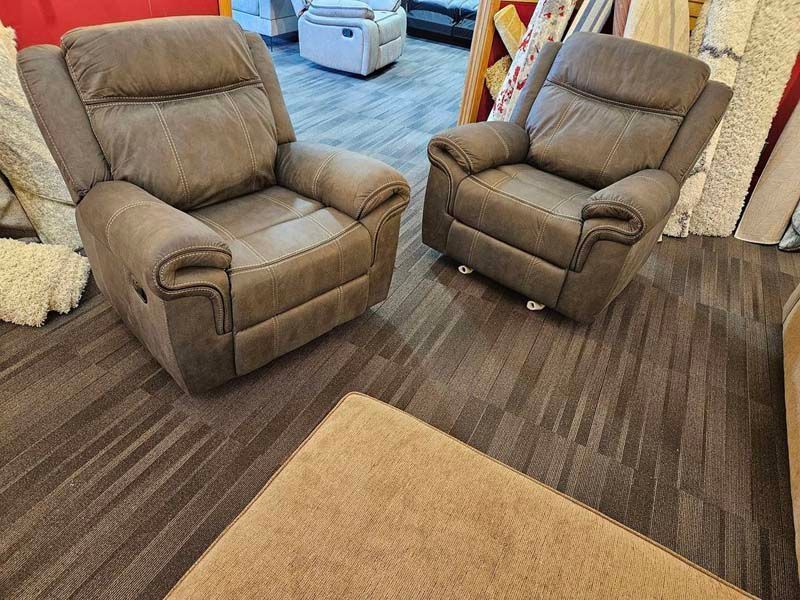 Two brown reclining armchairs on a patterned floor, with a tan ottoman in the foreground.