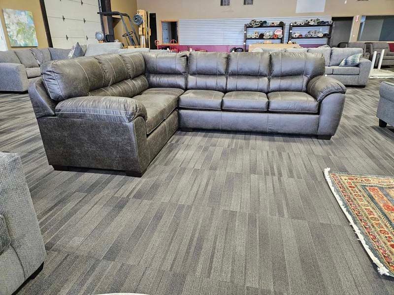 Gray sectional sofa on gray patterned flooring in a store.