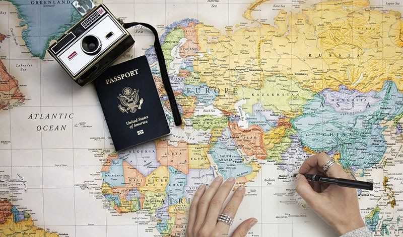 camera, passport, and map with someone planning a trip