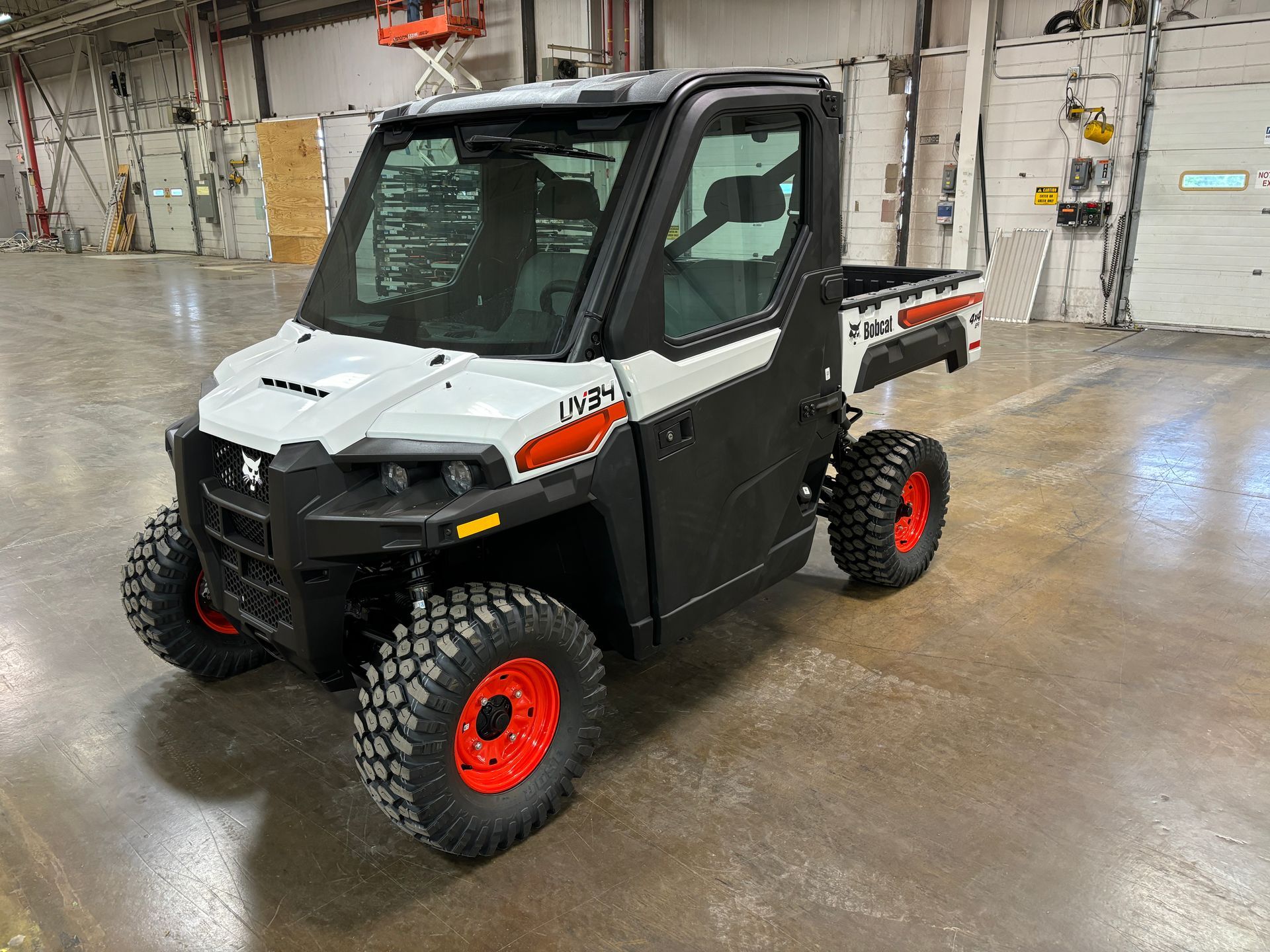 White and black Bobcat UTV with red wheels, indoors.