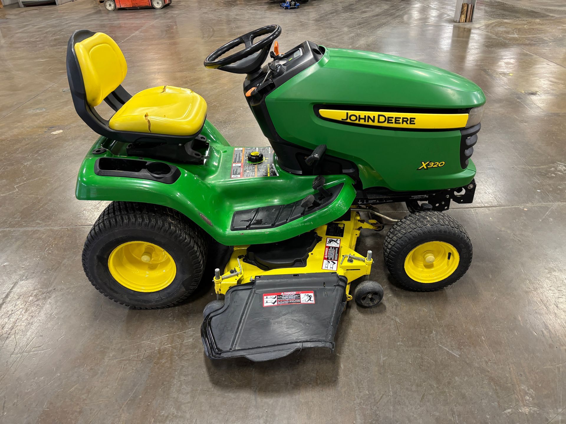 John Deere green and yellow riding lawn mower on a concrete floor.