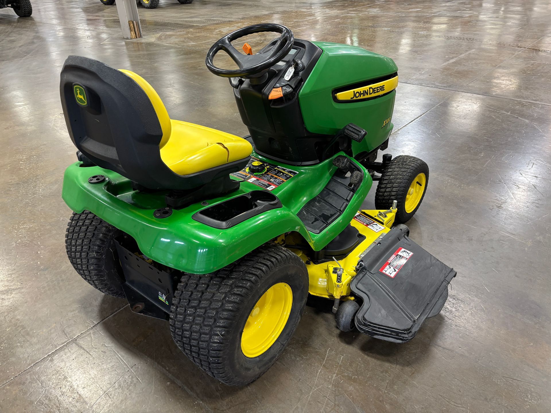 John Deere riding lawn mower, green and yellow, on a reflective surface.