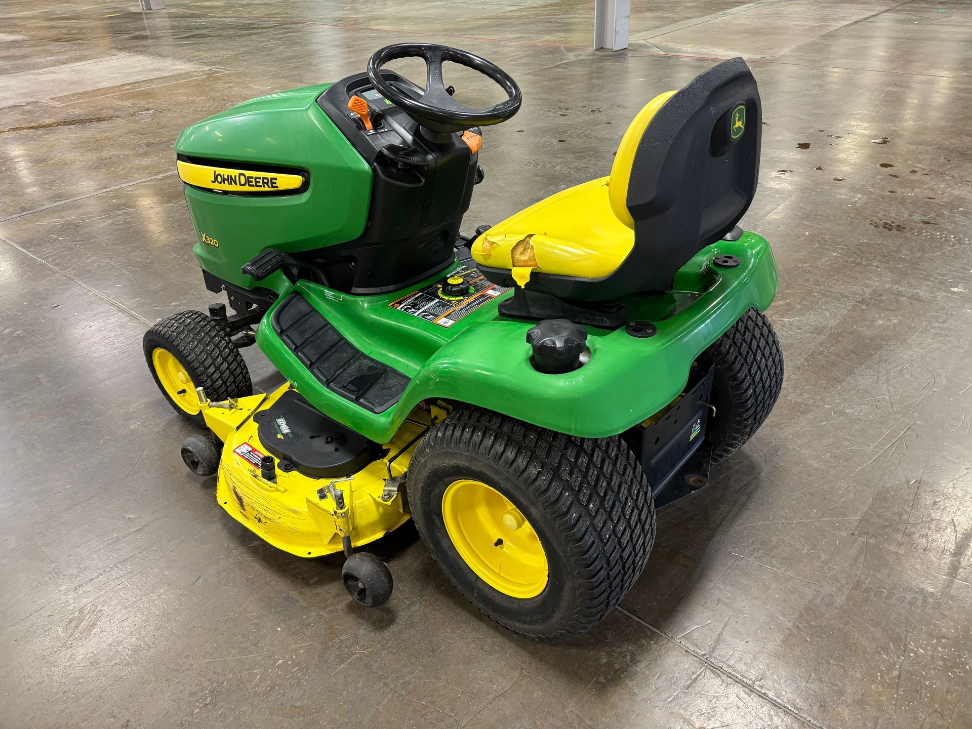 John Deere riding lawn mower, green and yellow, on a concrete surface.