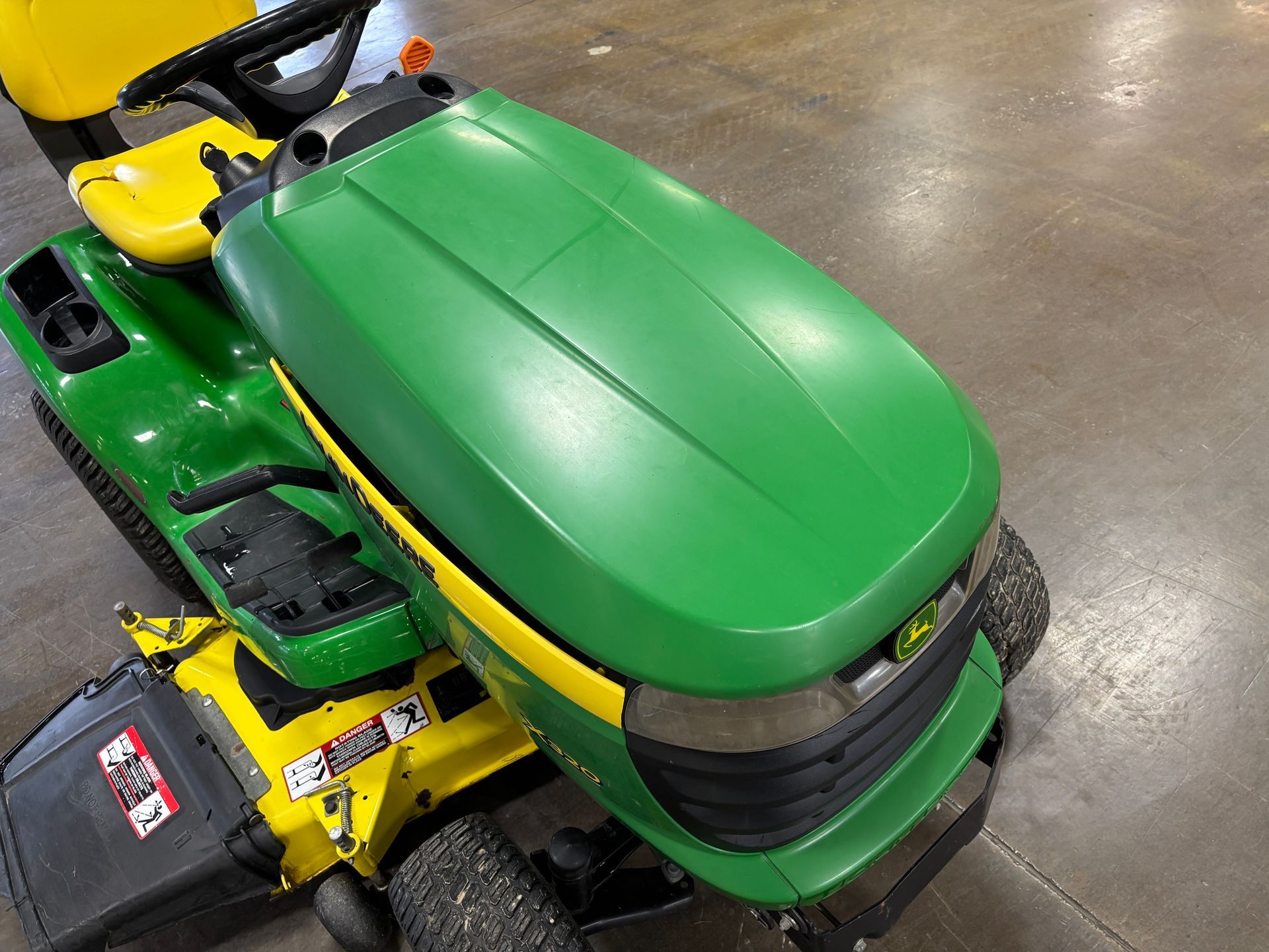 Green and yellow John Deere riding lawnmower, angled view.