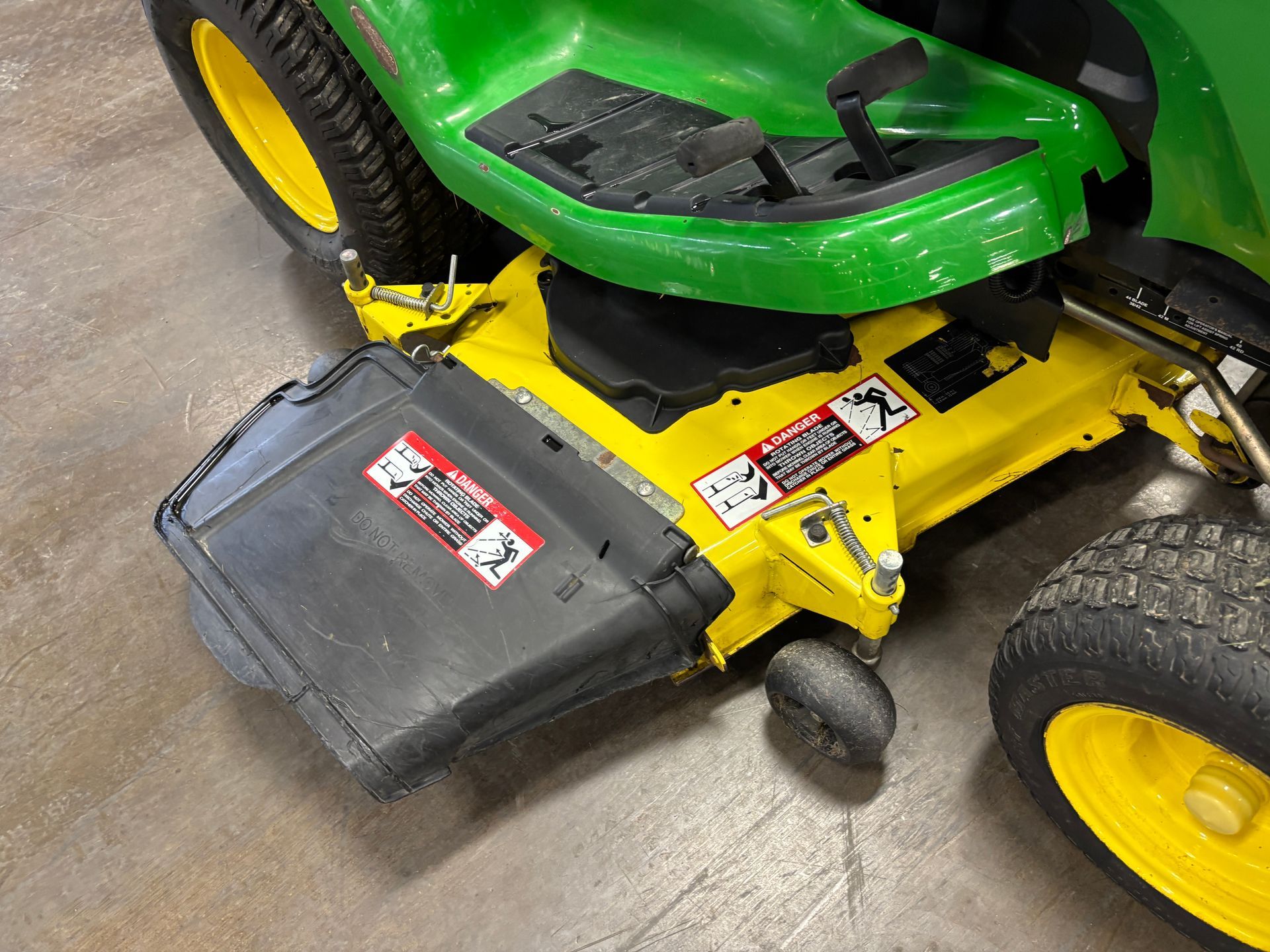 John Deere riding lawn mower with yellow and green accents, black collection bin.