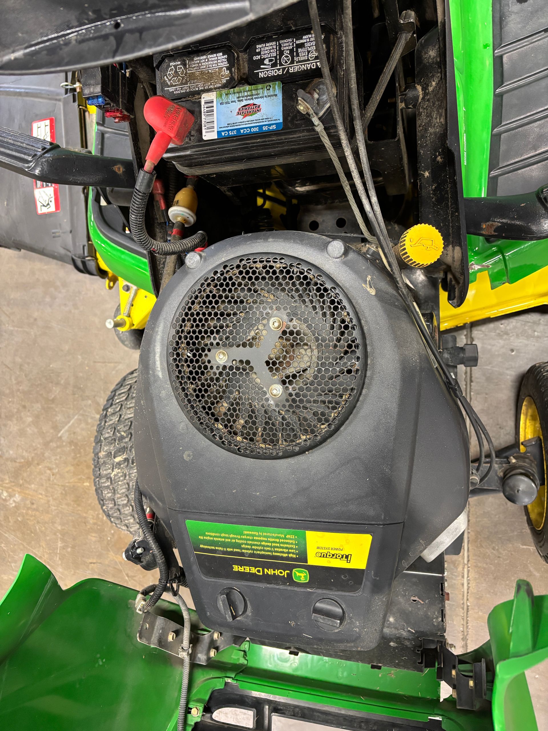 John Deere riding lawn mower engine. Black engine cover with fan, yellow and green details.