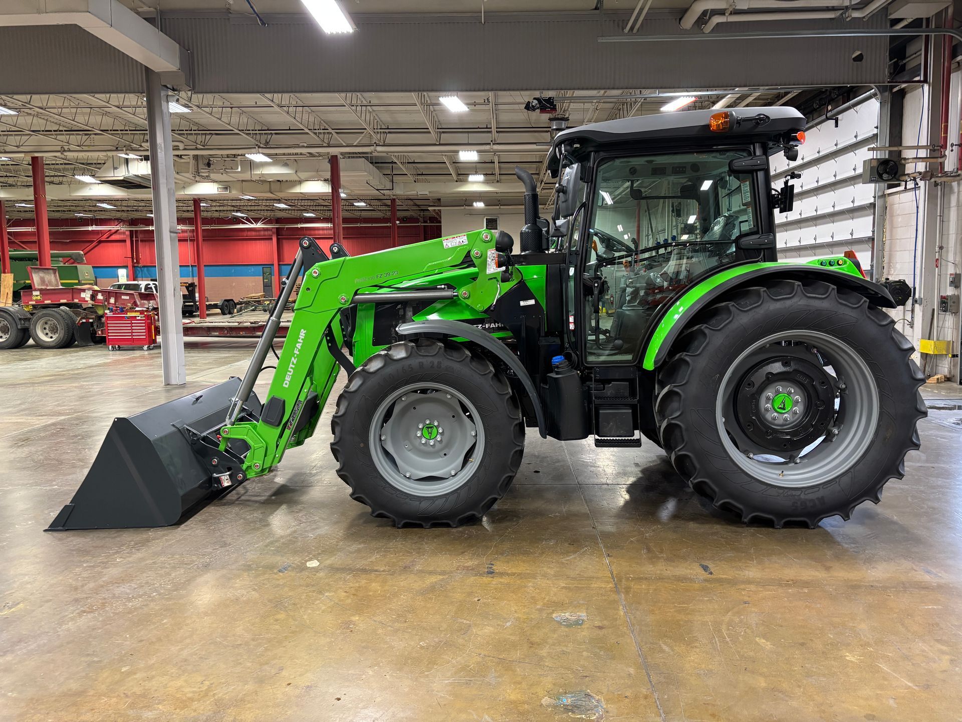 Green tractor with loader inside a warehouse.