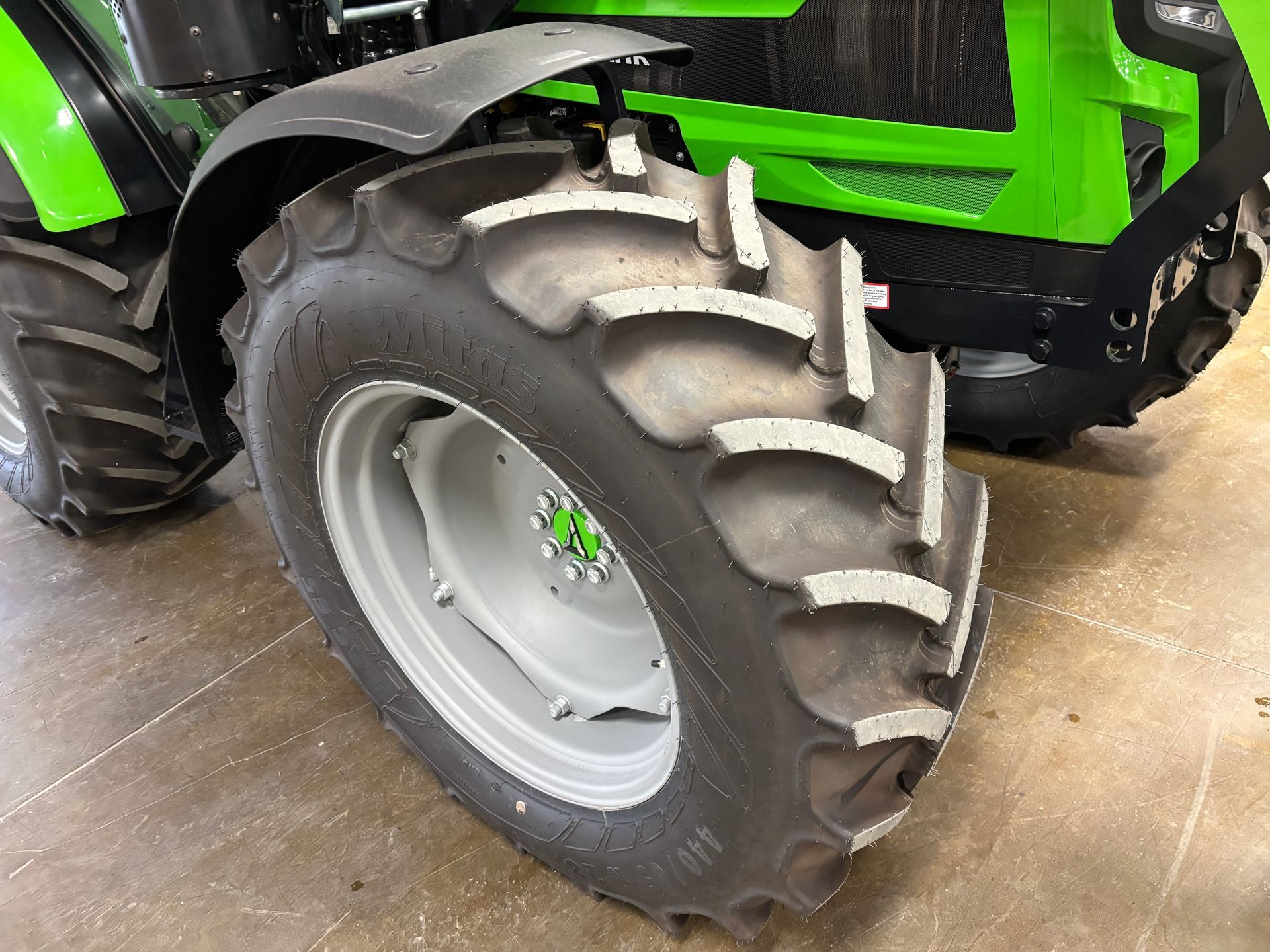 Close-up of a green and black tractor front wheel with large, textured tire.